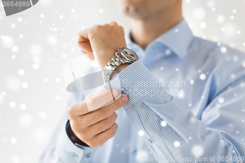 Image of close up of man fastening buttons on shirt sleeve