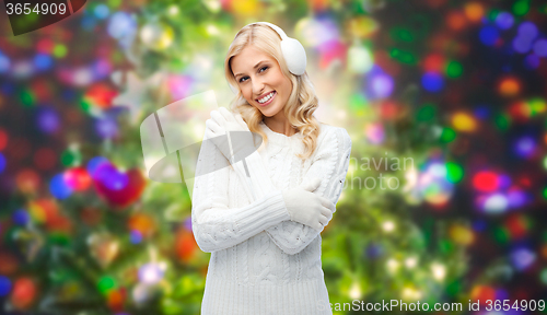 Image of smiling young woman in winter earmuffs and sweater