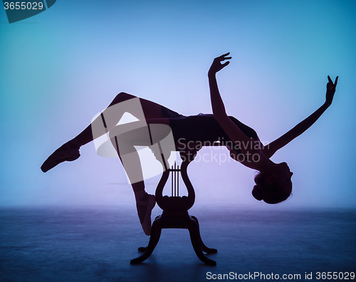 Image of The silhouette of young ballerina on the wooden table 