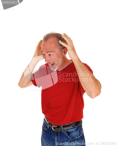 Image of Old man scared with hands on head.