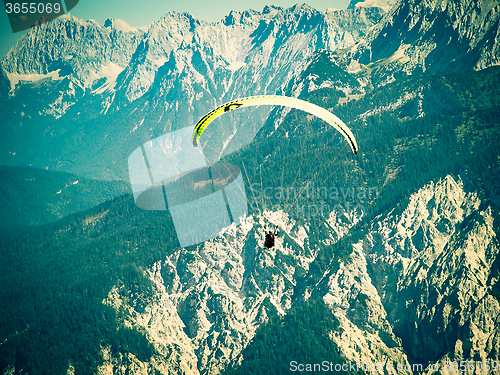 Image of Paraglider flying over high and rugged range of Alps mountains