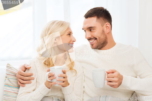Image of happy couple with cups drinking tea at home