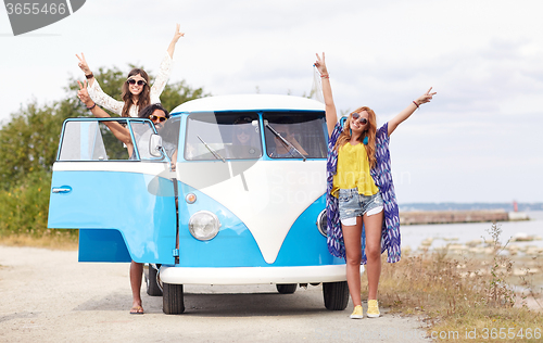 Image of smiling young hippie friends over minivan car