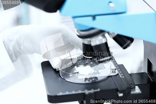 Image of close up of hand with microscope and powder sample