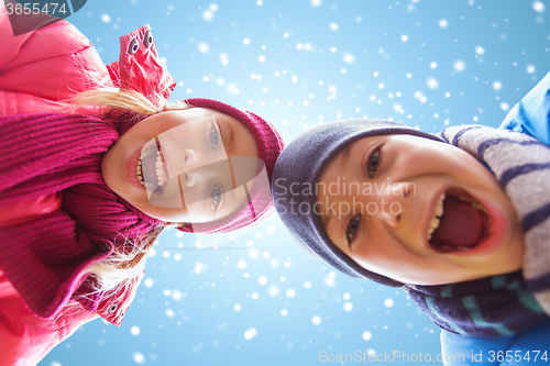 Image of happy little boy and girl over blue sky with snow