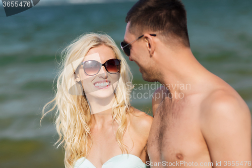 Image of happy couple in swimwear walking on summer beach