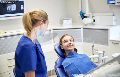 Image of happy female dentist with patient girl at clinic