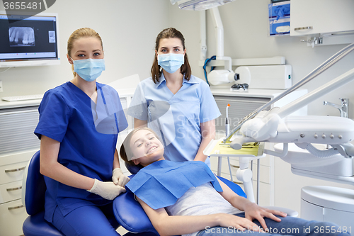 Image of happy female dentist with patient girl at clinic