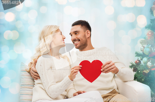 Image of happy couple with red heart at home for christmas