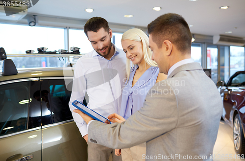 Image of happy couple with car dealer in auto show or salon