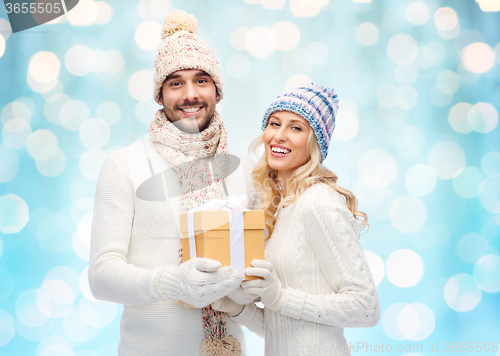 Image of smiling couple in winter clothes with gift box