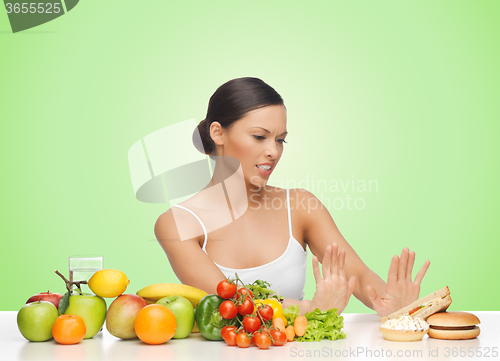 Image of woman with fruits rejecting hamburger