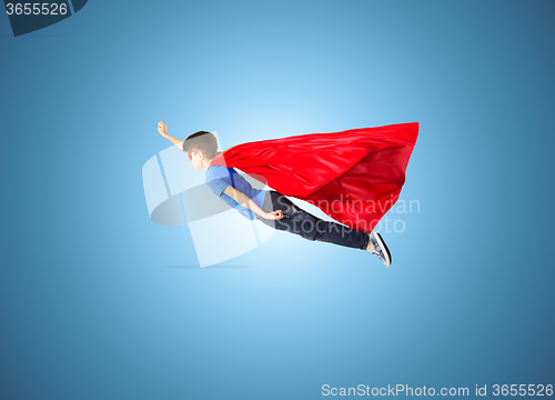 Image of boy in red superhero cape and mask flying on air