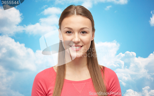 Image of smiling young woman or teenage girl over blue sky