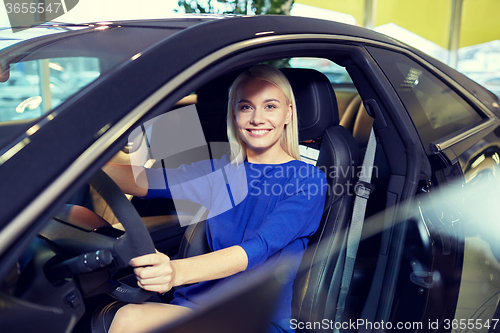 Image of happy woman inside car in auto show or salon