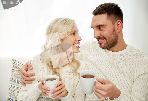 Image of happy couple with cups drinking tea at home