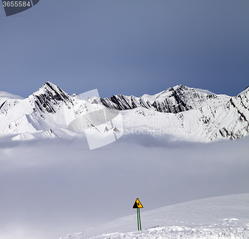 Image of Mountains in mist and warning sing on off-piste slope