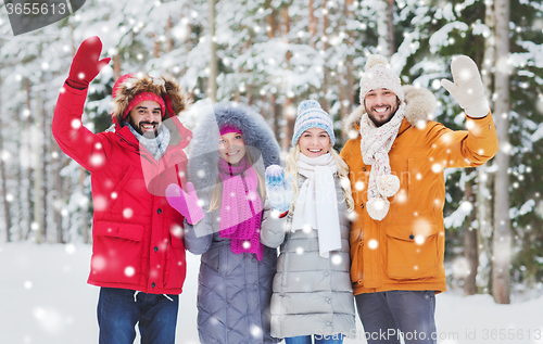 Image of group of friends waving hands in winter forest