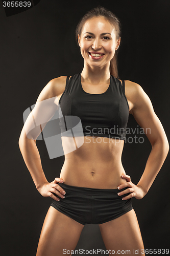 Image of Muscular young woman athlete looking in camera on black 