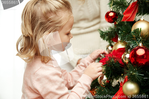 Image of little girl decorating christmas tree at home