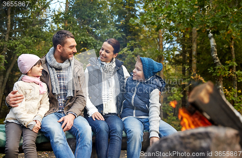 Image of happy family sitting on bench at camp fire