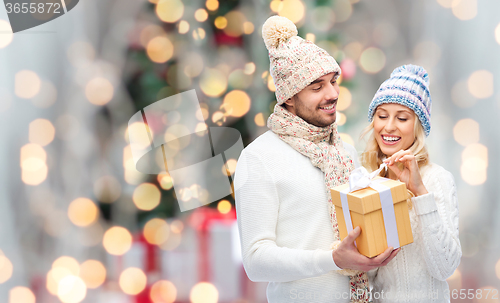 Image of smiling couple in winter clothes with gift box