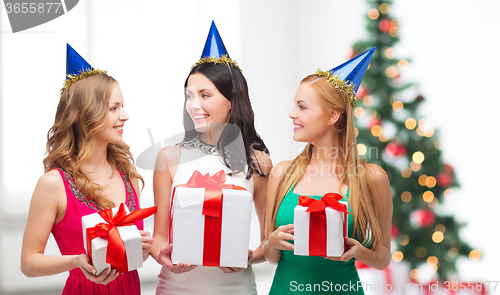 Image of three smiling women in blue hats with gift boxes