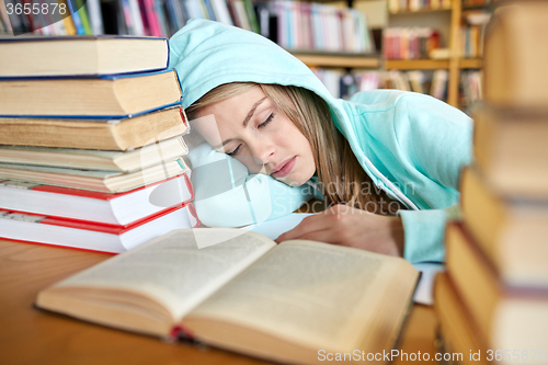 Image of student or woman with books sleeping in library