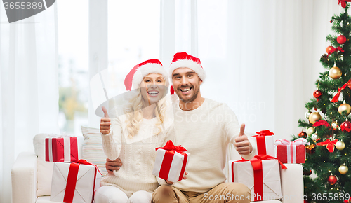 Image of happy couple with christmas gifts and thumbs up