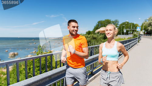 Image of smiling couple running at summer seaside