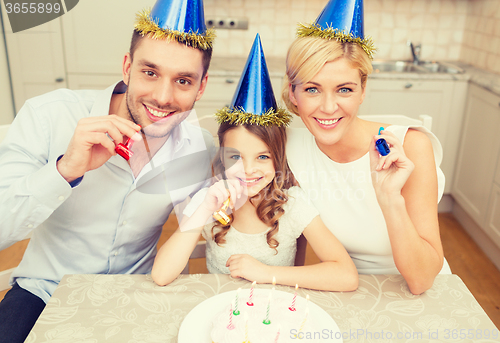 Image of smiling family in blue hats blowing favor horns