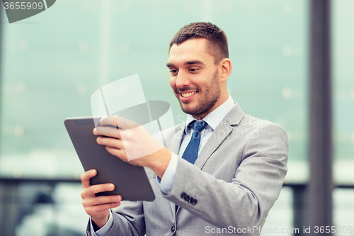 Image of smiling businessman with tablet pc outdoors