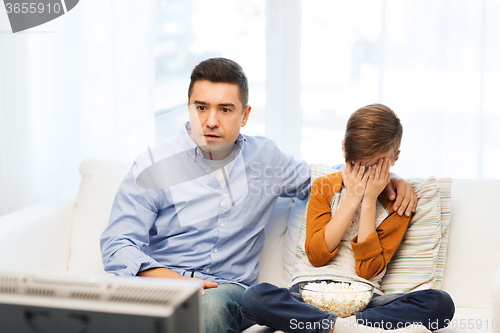 Image of father and son watching horror movie on tv at home