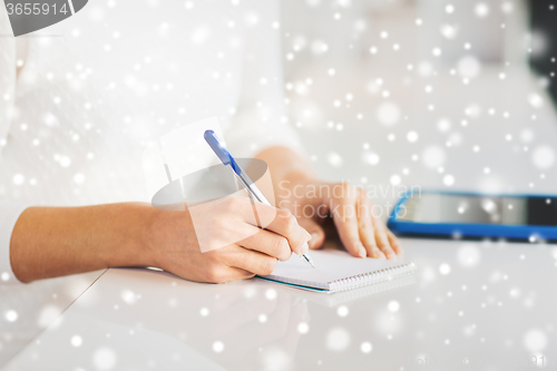 Image of close up of hands with pen writing to notepad