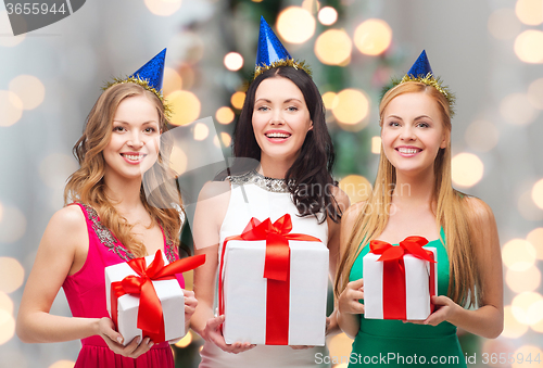 Image of smiling women in party caps with gift boxes