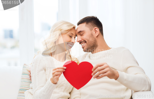 Image of happy couple with red heart hugging at home
