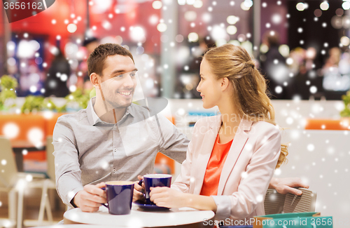 Image of happy couple with shopping bags drinking coffee