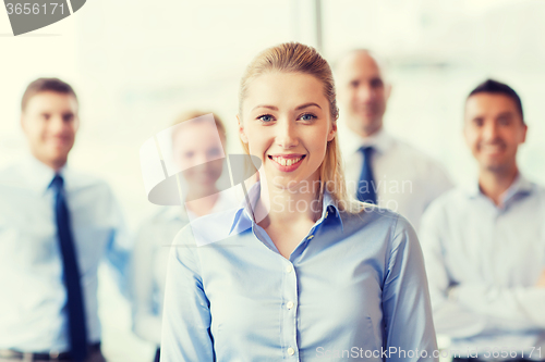 Image of smiling businesswoman with colleagues in office