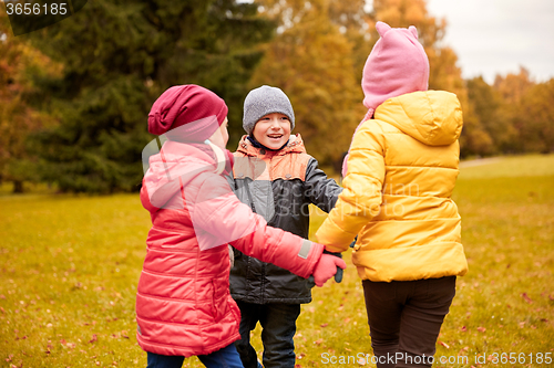 Image of children holding hands and playing in autumn park