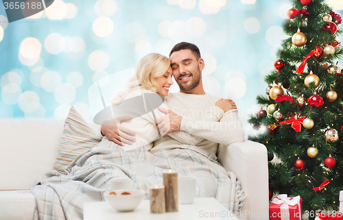 Image of happy couple hugging on couch at christmas