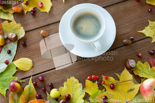 Image of close up of coffee cup on table with autumn leaves