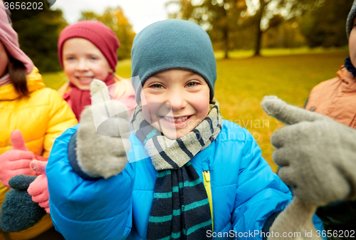 Image of happy children showing thumbs up in autumn park