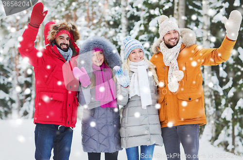 Image of group of friends waving hands in winter forest