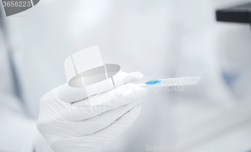 Image of close up of scientist hand with test sample in lab