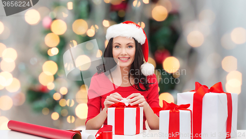 Image of smiling woman in santa helper hat packing gifts