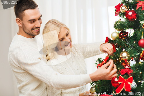 Image of happy couple decorating christmas tree at home