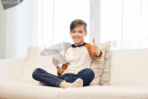 Image of smiling boy with tablet showing thumbs up at home