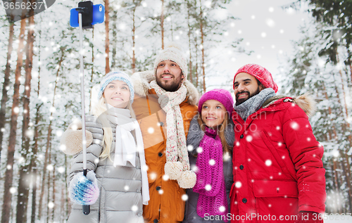 Image of smiling friends with smartphone in winter forest