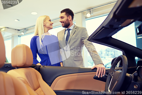 Image of happy couple buying car in auto show or salon