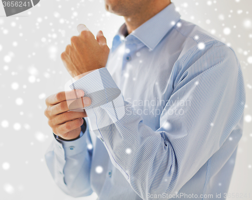 Image of close up of man fastening button on shirt sleeve